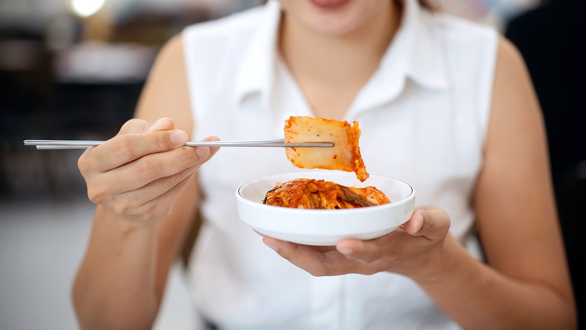 Woman eating kimchi with chopsticks