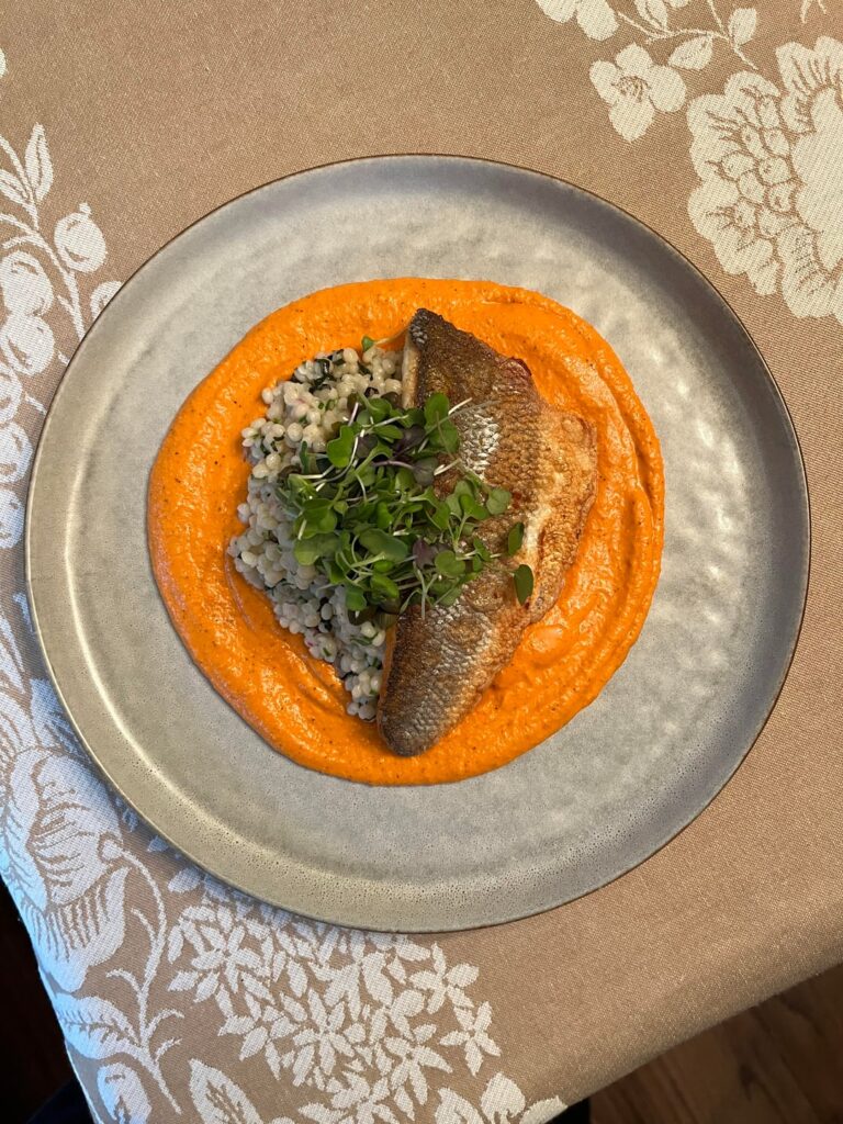 Romesco, couscous with herbs, pan-seared branzino, capers, and microgreens