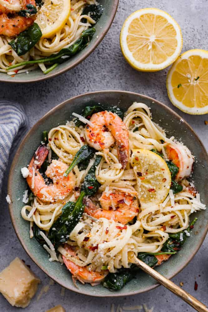Lemon Garlic Parmesan Shrimp Pasta is made in just one pot and ready in 30 minutes! Fresh shrimp is cooked in a buttery lemon garlic sauce and tossed in fresh parmesan cheese and pasta. It's unbelievably good and sure to become a new favorite! Lemon garlic parmesan shrimp pasta in a bowl with fresh lemon cut in half next to it.