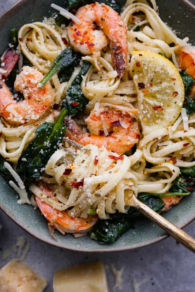 Lemon Garlic Parmesan Shrimp Pasta is made in just one pot and ready in 30 minutes! Fresh shrimp is cooked in a buttery lemon garlic sauce and tossed in fresh parmesan cheese and pasta. It's unbelievably good and sure to become a new favorite! A close up on lemon garlic parmesan shrimp pasta in a bowl.