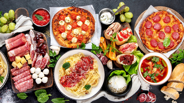 A display of popular Italian food, including pasta, pizza, cheese, and salami.