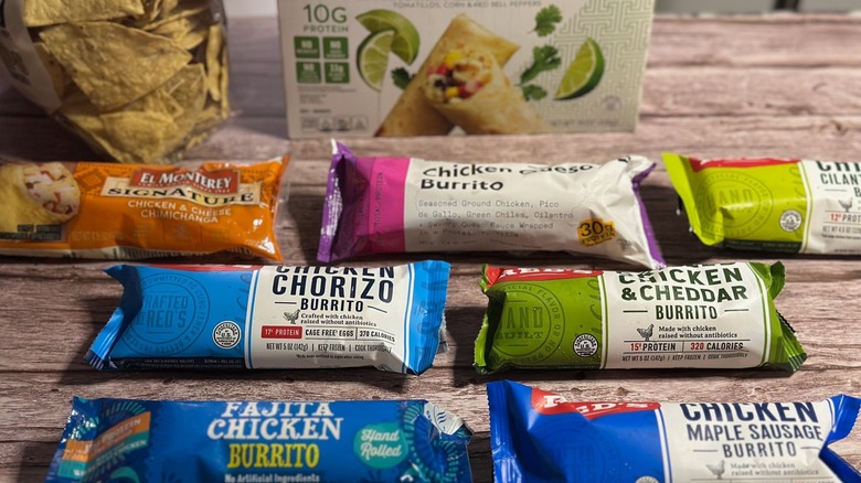 Line of different brands of frozen chicken burritos on wooden table