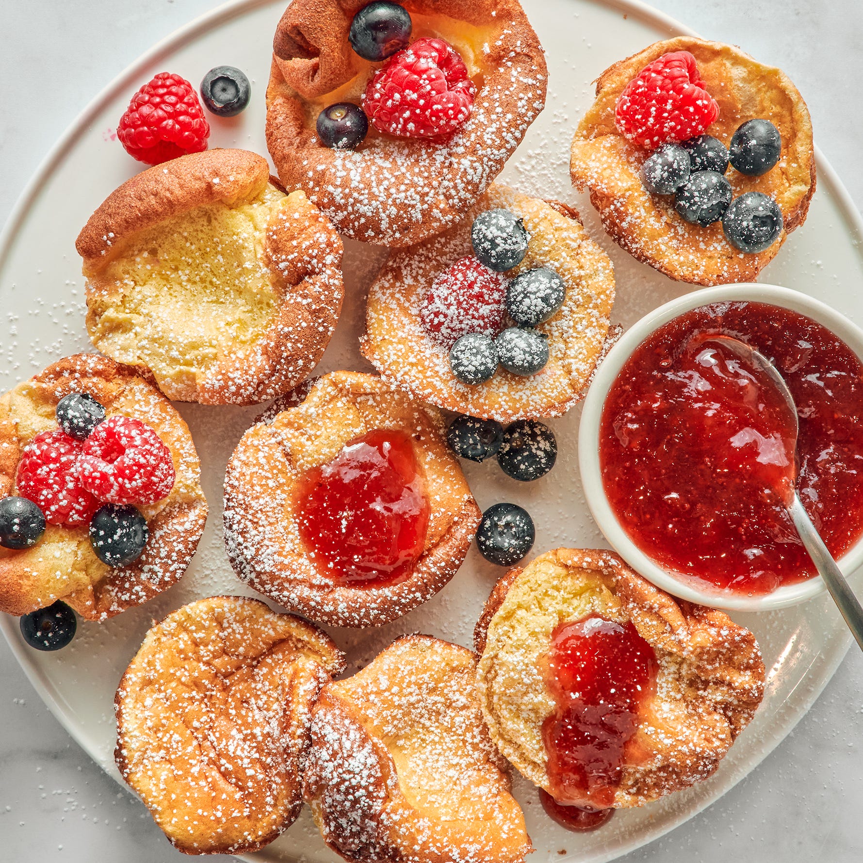 mini dutch baby pancakes with berries jam and confectioners sugar