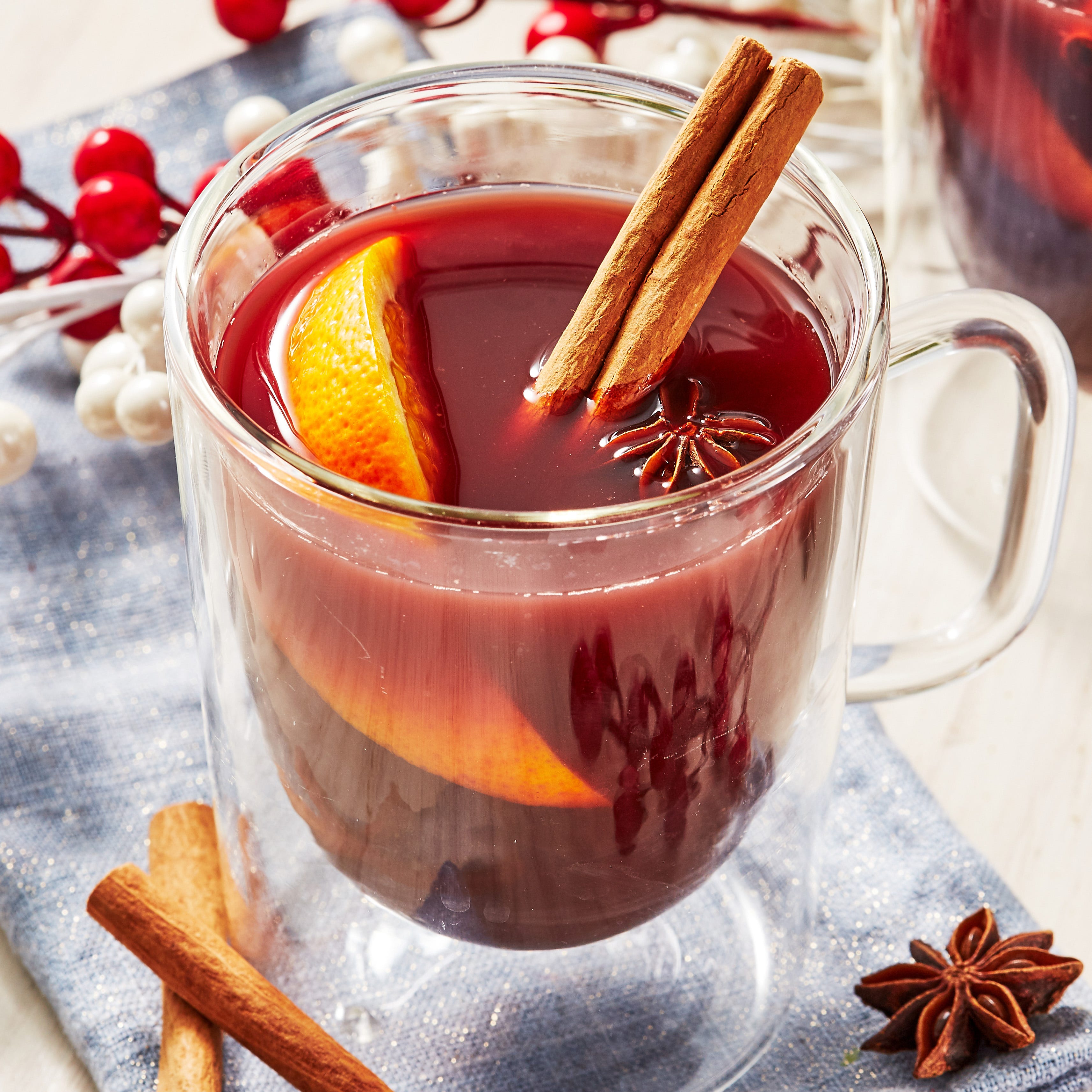 nonalcoholic mulled wine in a glass mug garnished with cinnamon sticks, star anise, and an orange wedge