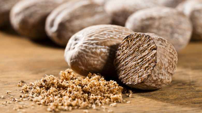 closeup of nutmeg whole and shaved on wood