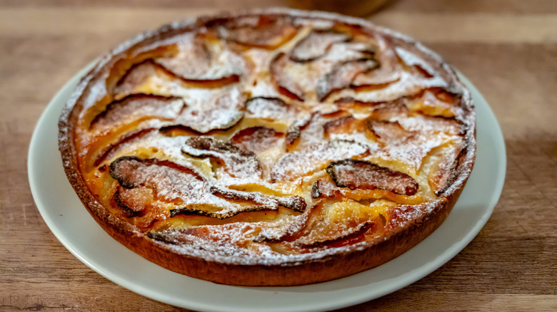 Baked apple tart from Normandy on a white plate on a wooden table