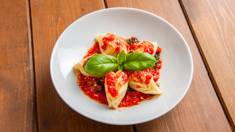 Culurgiones served in a simple tomatoe sauce with basil leaves on top