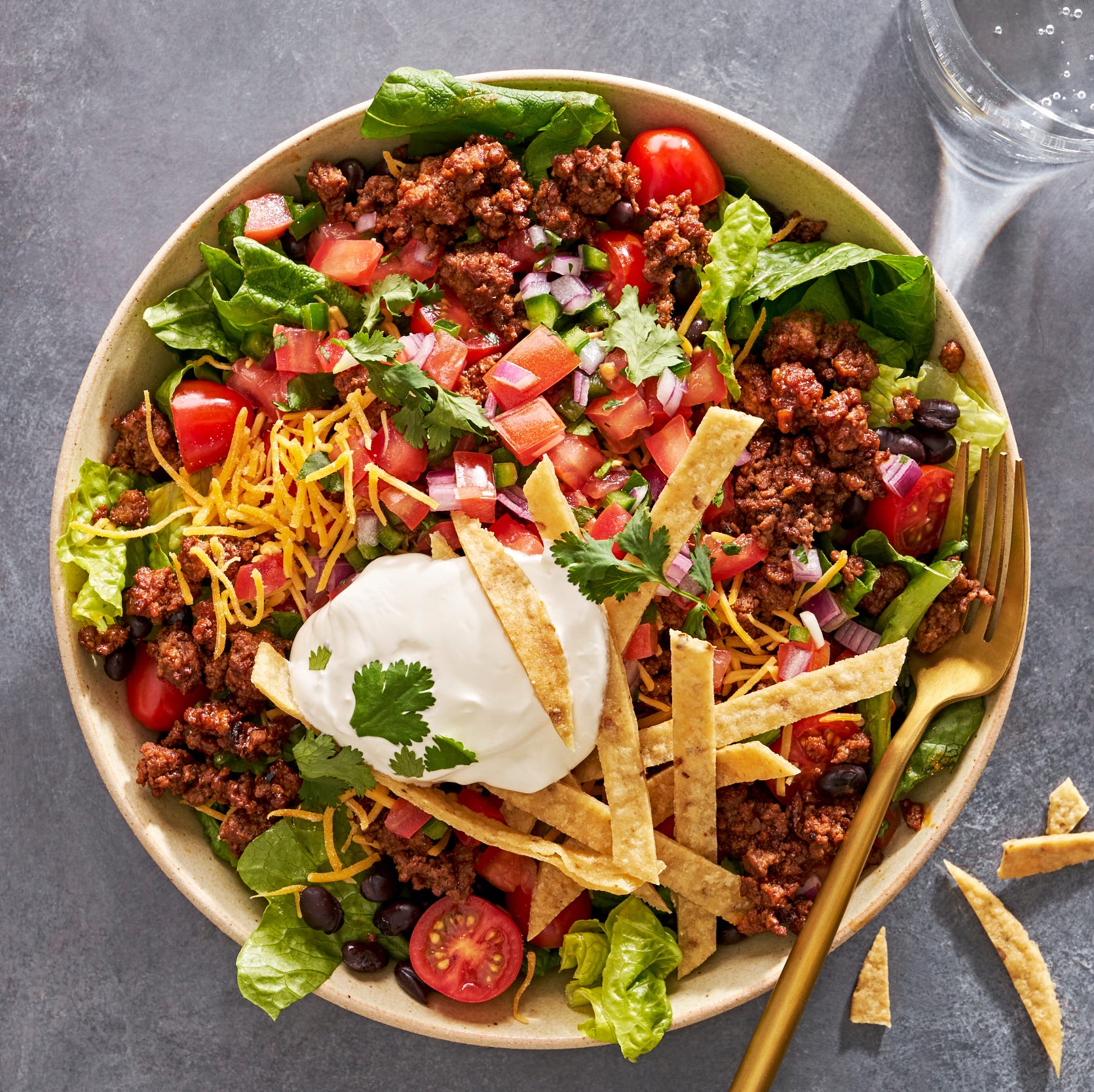 taco salad with sour cream, tomatoes, ground beef, and tortilla strips