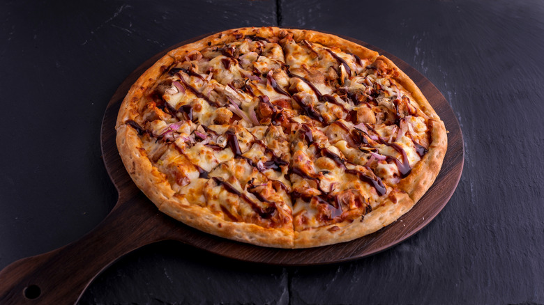 BBQ CHICKEN pizza isolated on cutting board top view on dark background Italian fast food
