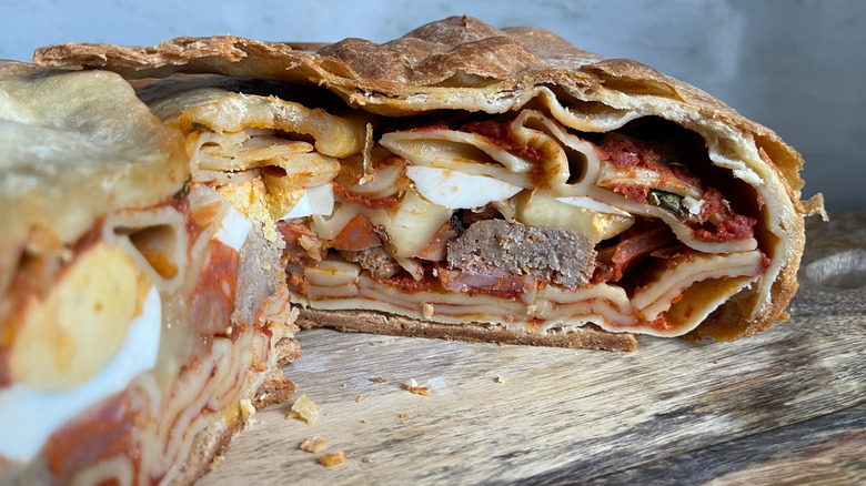 Italian timpano stuffed with meat, cheese, and tomato sauce