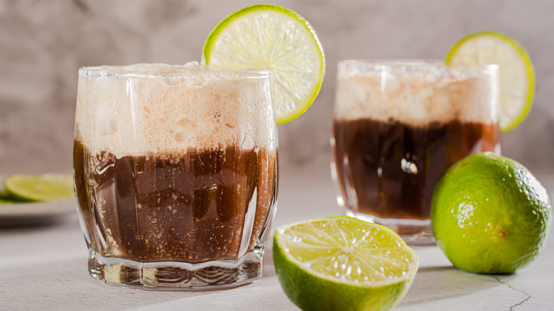 Two glasses of brown soda and cream with lime slices on the rims