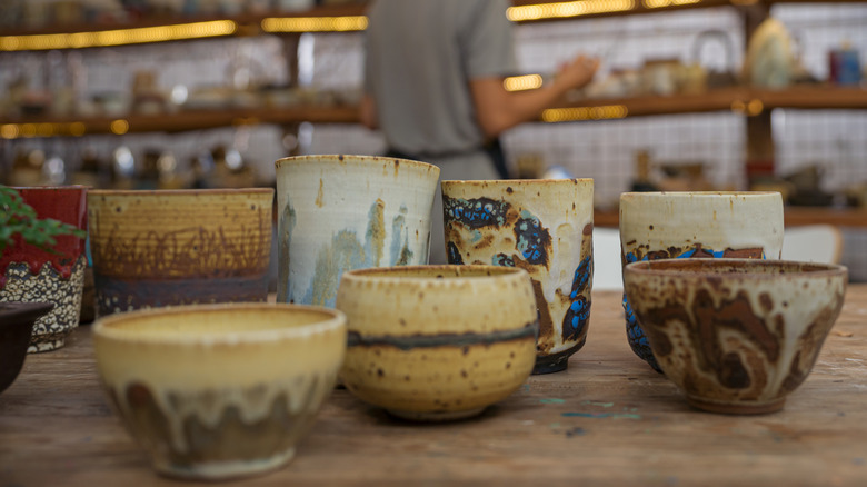 Handmade old clay pots with pencils and other stuff on the table.