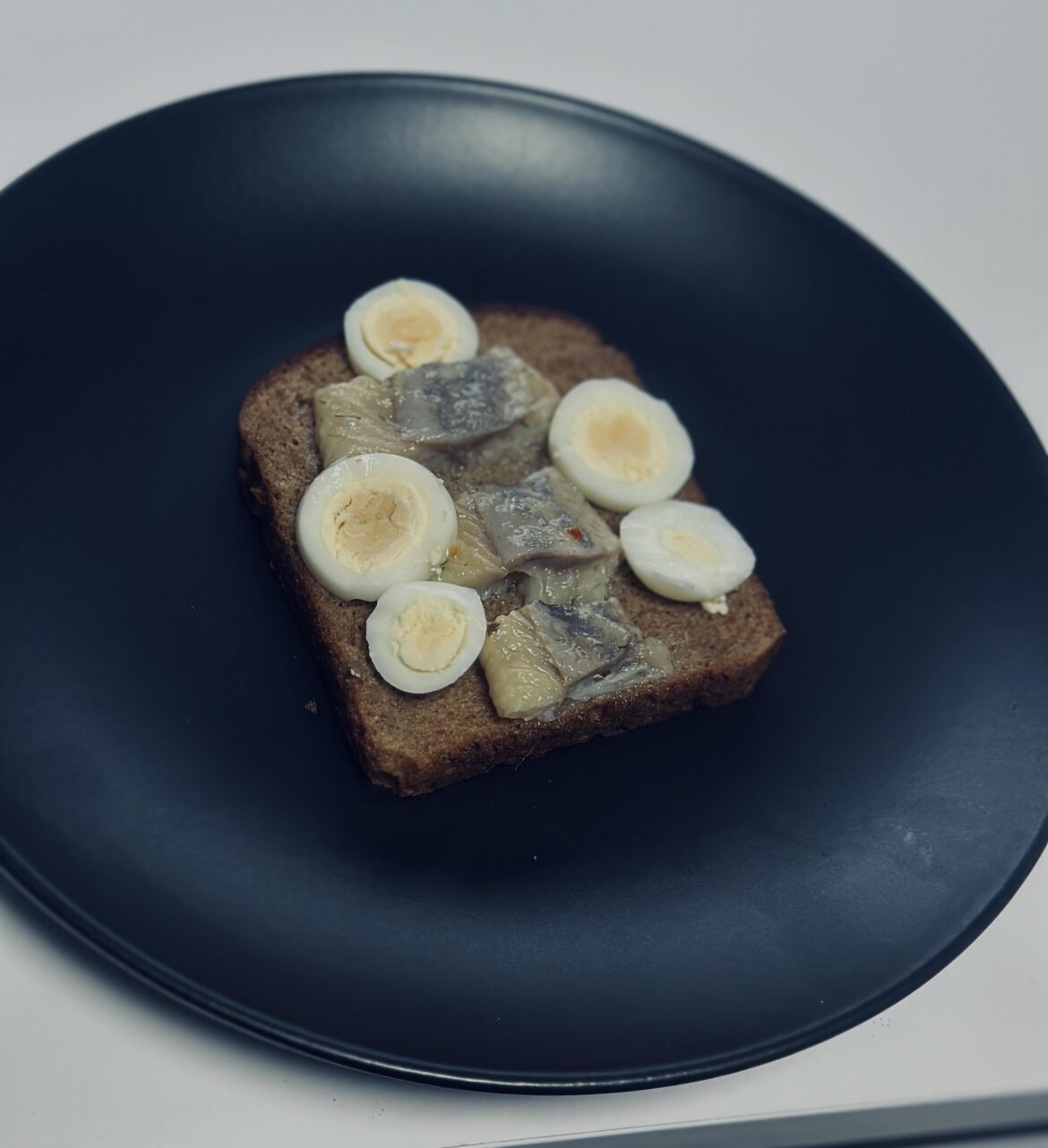 Looks awful but tastes amazing: black bread with herring and quail egg