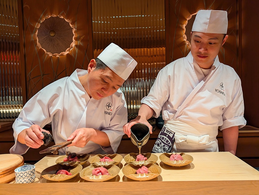 Two sushi chefs pour broth and shave truffles over seven bowls with barely-cooked wagyu.