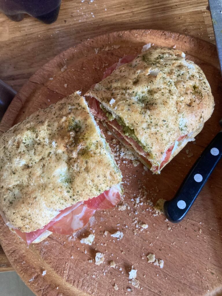Sea salt and rosemary bread from lidl bakery. Pesto for the spread. The meat is prosciutto and gabagool. The cheese is mozzarella I don’t remember adding that much. The veg is tomato.