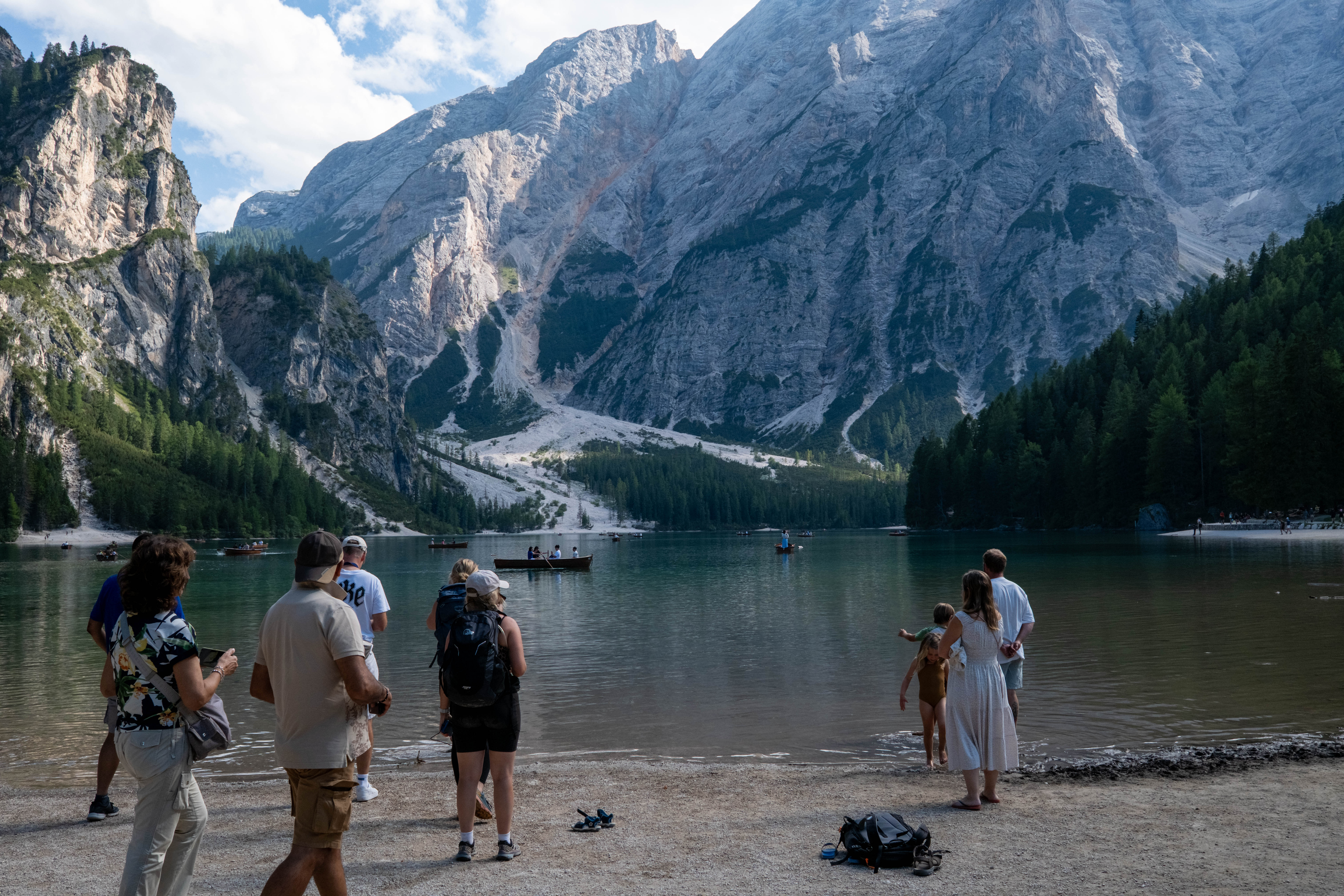 Lake Braies in the Dolomites with people on the shore and boats on the water.