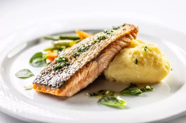 Baked salmon fillet with mashed potatoes and English vegetables on a white isolated background.