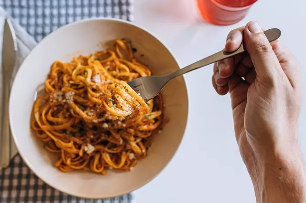 Unrecognizable man eating fresh tagliatelle pasta with bolognese sauce