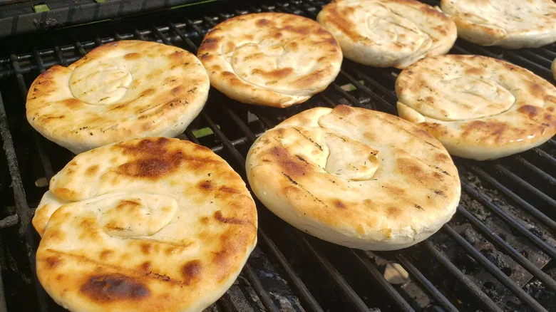 Several pieces of flatbread grilled golden-brown on grill grates
