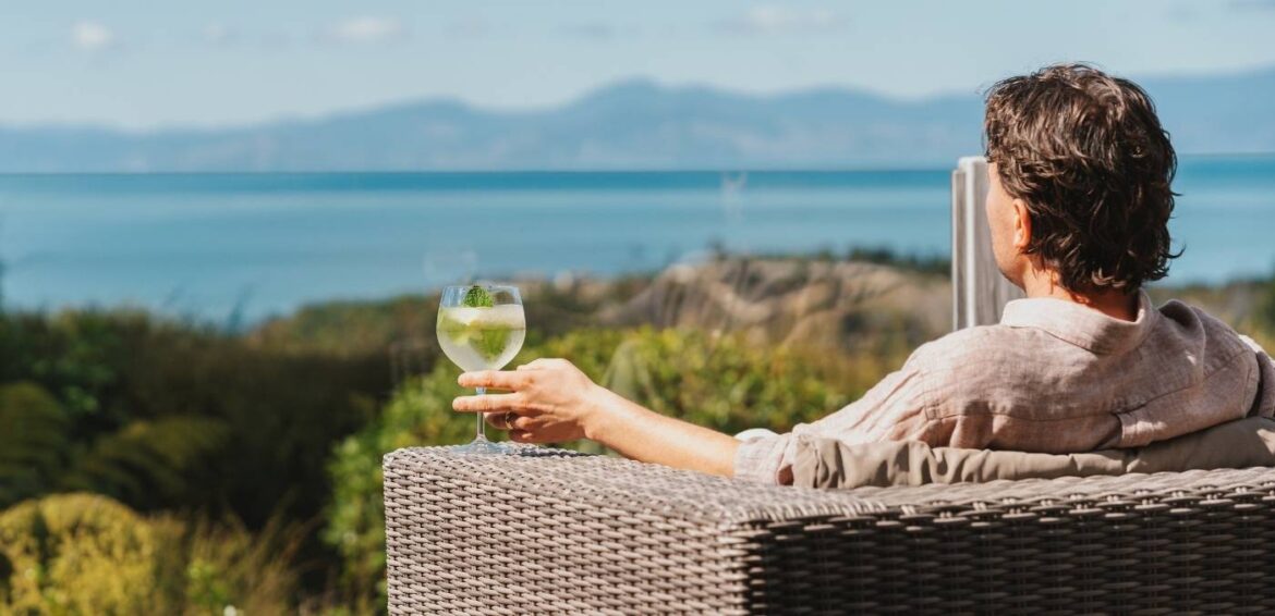 man drinking wine overlooking coastal views