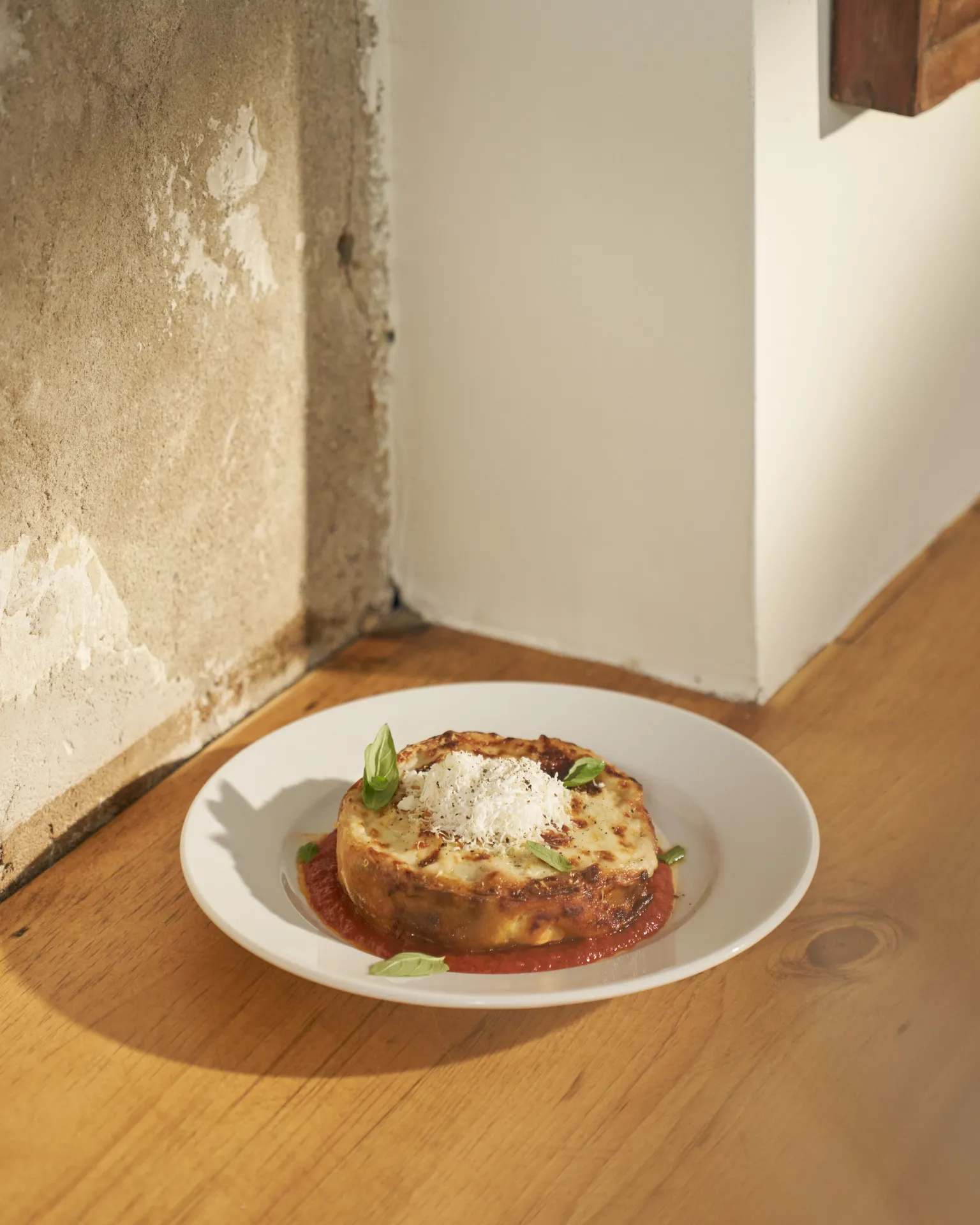 A pasta dish sitting on a white table with a concrete wall in the background