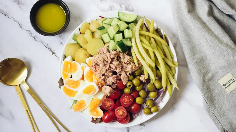 Salade Niçoise with dressing and serving spoons