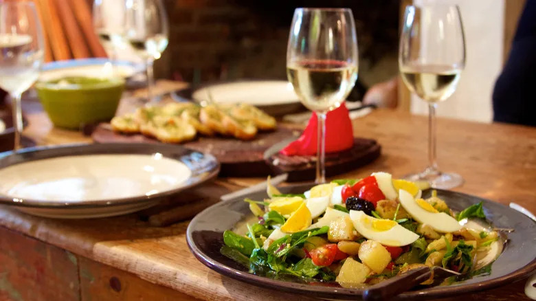 Salade Niçoise with wine glasses on a table