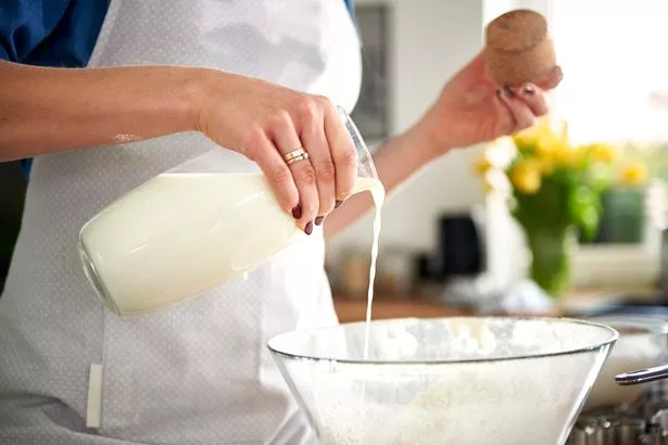 Woman pouring milk into a bowl in the kitchen