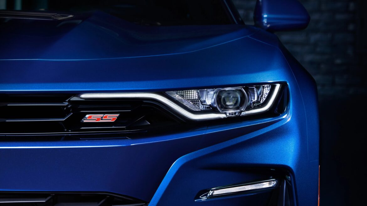 Close-up of the front left headlight and grille of a blue Chevrolet Camaro SS with illuminated LED daytime running lights.