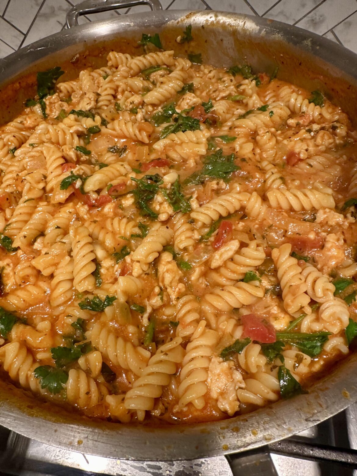 Rotini with ground chicken and parsley in red sauce.