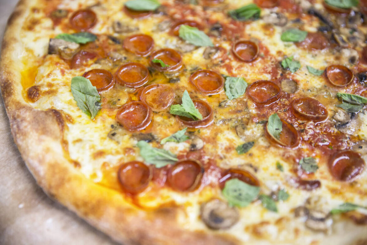 A freshly cooked Olde New York specialty pizza, made with thick slices of mozzarella, old schoo ...