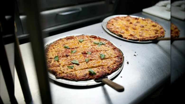 Two thin crust pizzas cut into squares