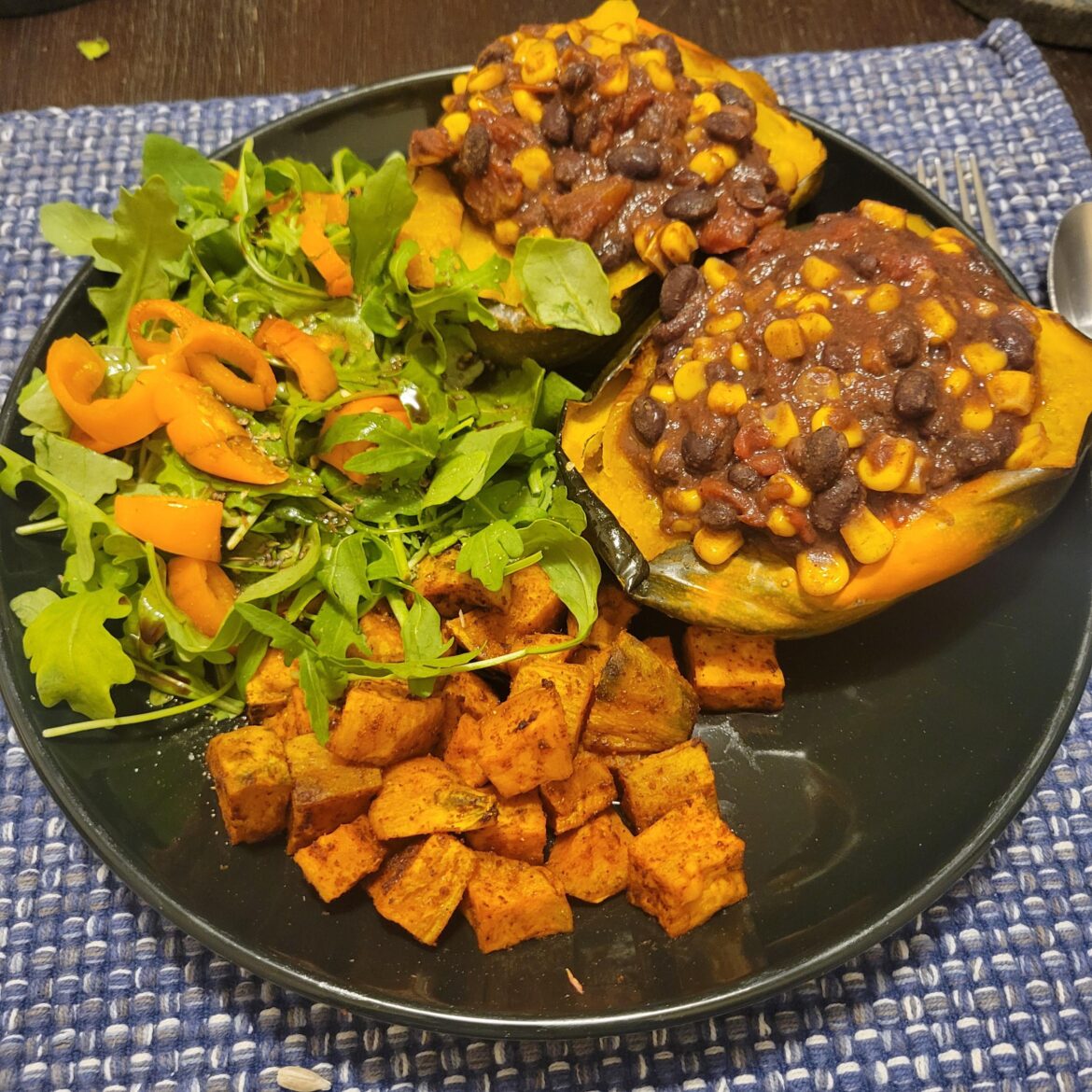 Black bean and corn chili served in acorn squash bowls, with spiced herbed roasted sweet potatoes and arugula and pepper salad
