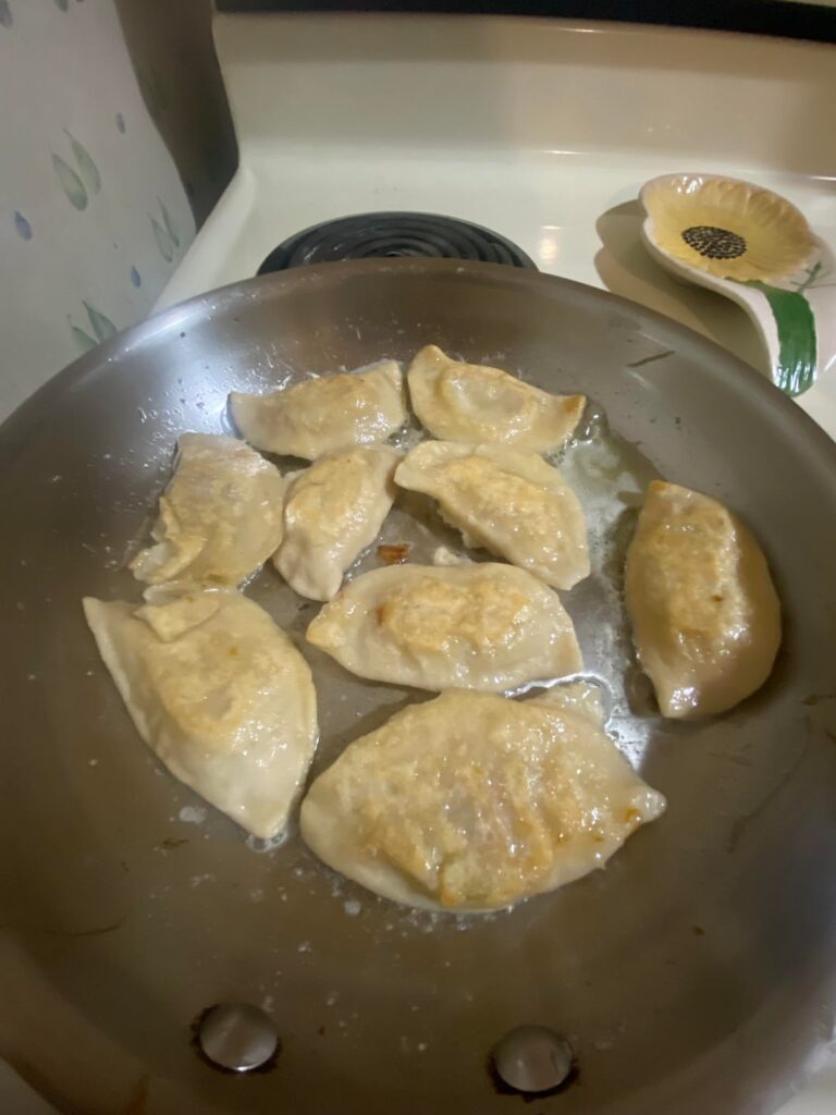 Homemade potato onion and bacon pierogies, sautéed onions, and sour cream and scallions to dip
