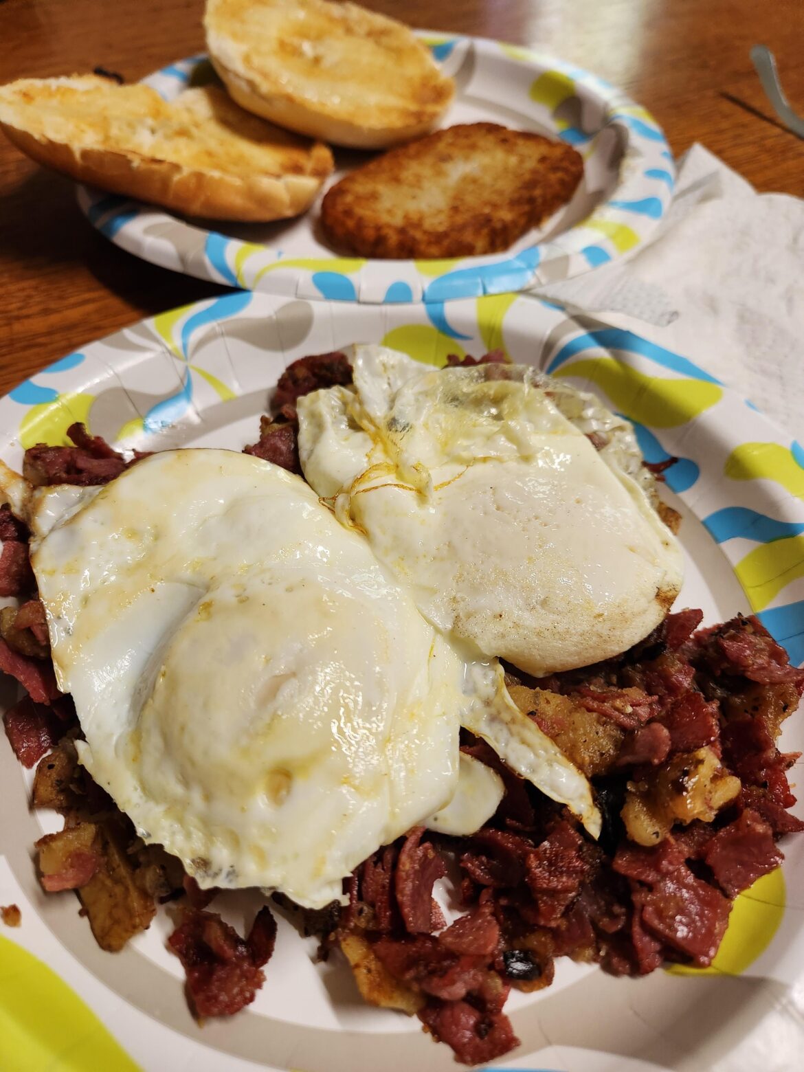 Homemade corned beef hash w runny eggs, hash browns and a bagel.