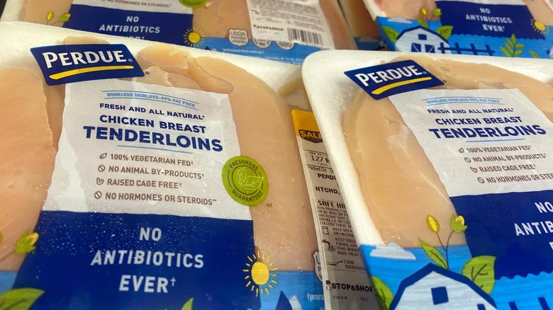 Packages of Perdue chicken breasts in the grocery store refrigerator section.