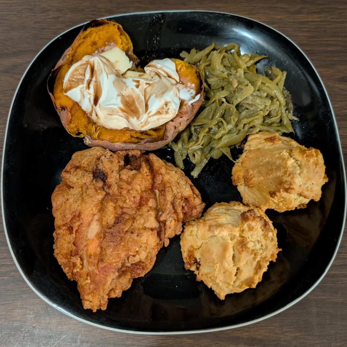 Fried chicken thigh, baked sweet potato, green beans, and biscuits