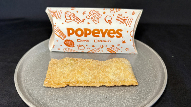 Popeyes apple pie on a plate in front of its box