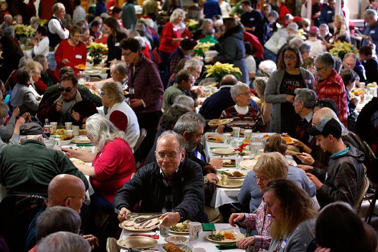 Rodney Jenness, of Lebanon, N.H., passes a plate of turkey to another at his table during the annual Lebanon Christmas Day Dinner in Lebanon, N.H., on Dec. 25, 2018. Listen Community Services, which serves six community meals a week at their White River Junction dining facility, began running the annual Christmas meal this year.  (Valley News - Geoff Hansen) Copyright Valley News. May not be reprinted or used online without permission. Send requests to permission@vnews.com.