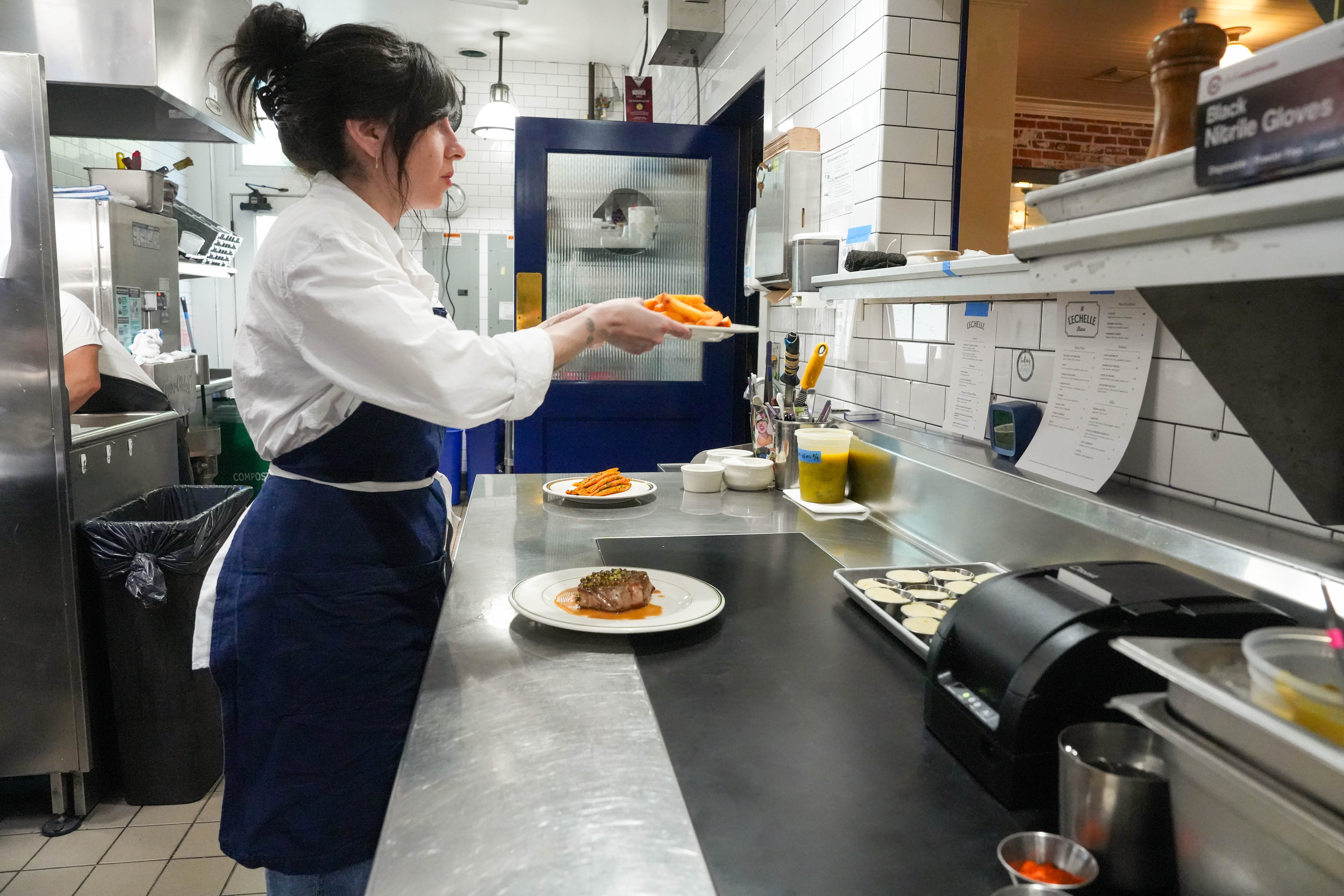 Executive chef Mika Paredes places a plate of frites through the pass in her Southeast Portland restaurant, L'Echelle, on Wednesday, August 13, 2025.