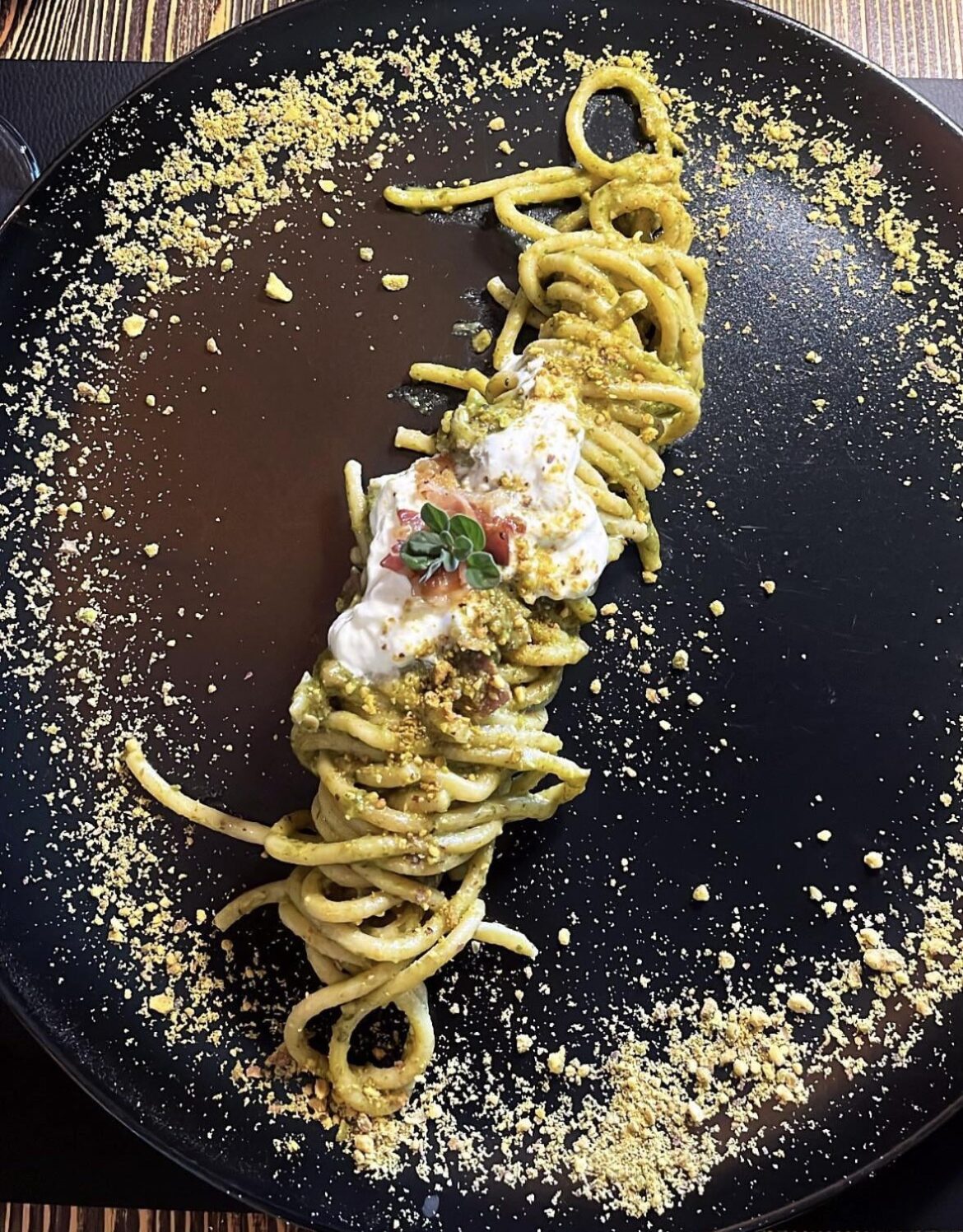 Spaghetti with pistachio pesto, stracciatella cheese, and bacon
