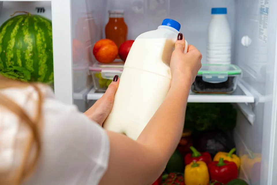 Female hand taking bottle of milk from a fridge close up