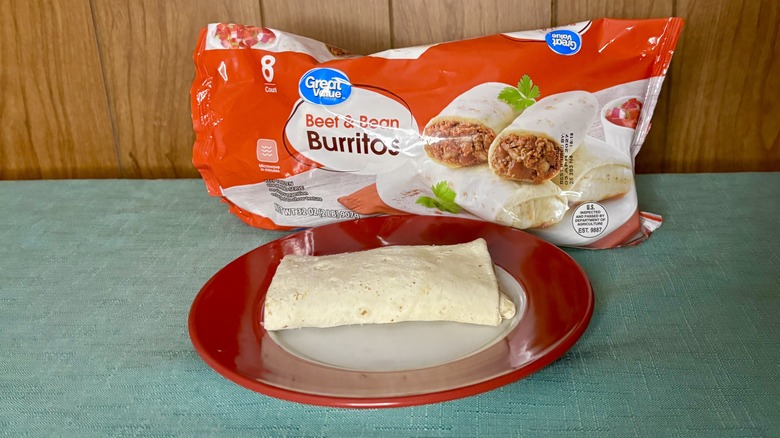 A single Great Value Beef and Bean burrito  on a red plate, in front of the value pack packaging