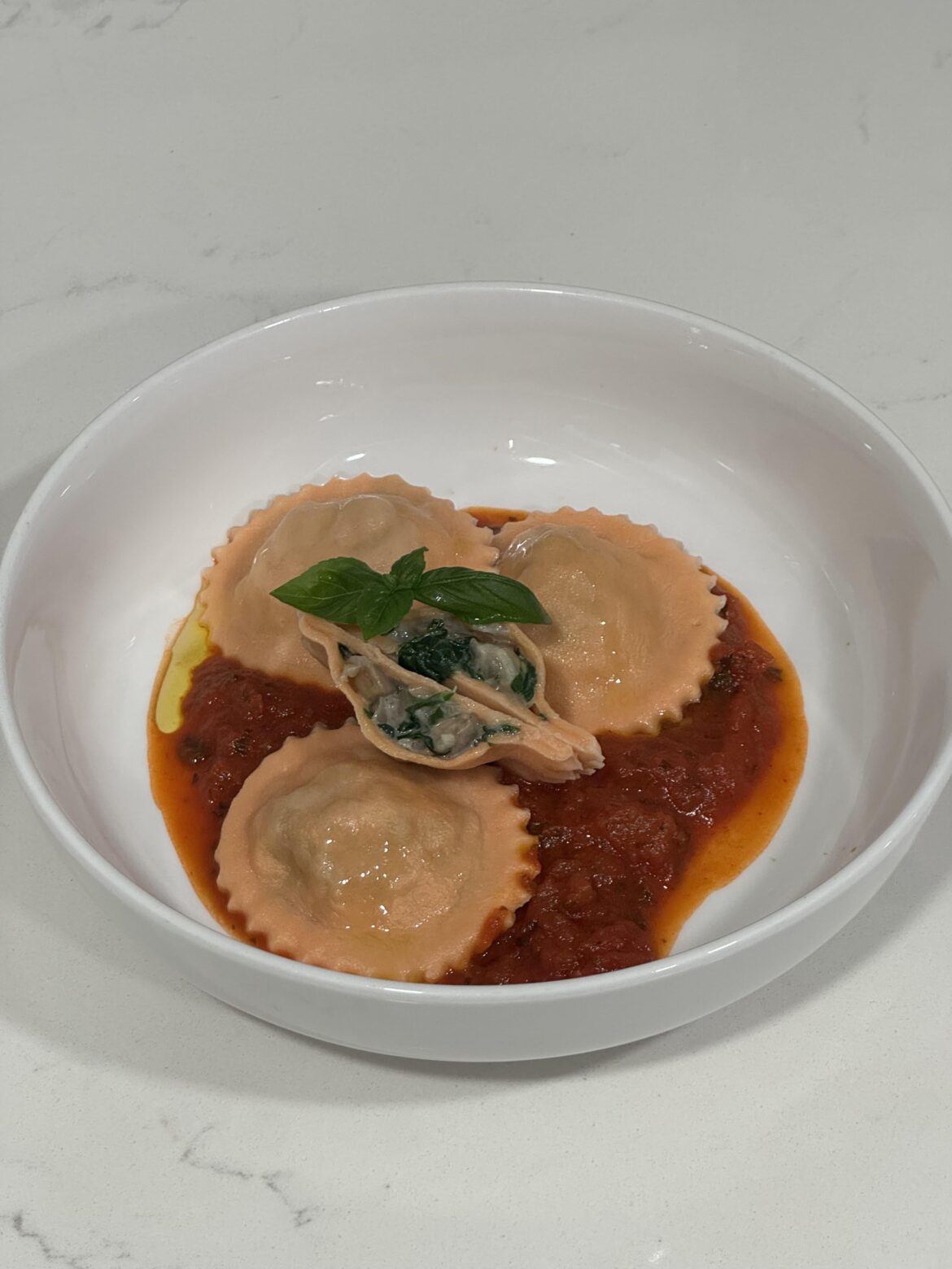 Ravioli with a filling consisting of mushroom, garlic, onion, spinach, and parmesan served over tomato sauce.