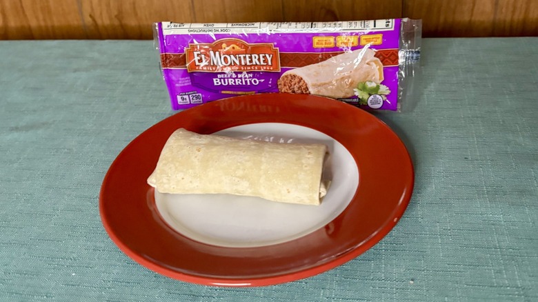 El Monterey's Beef and Bean Burrito  on a red plate, in front of the burrito's packaging