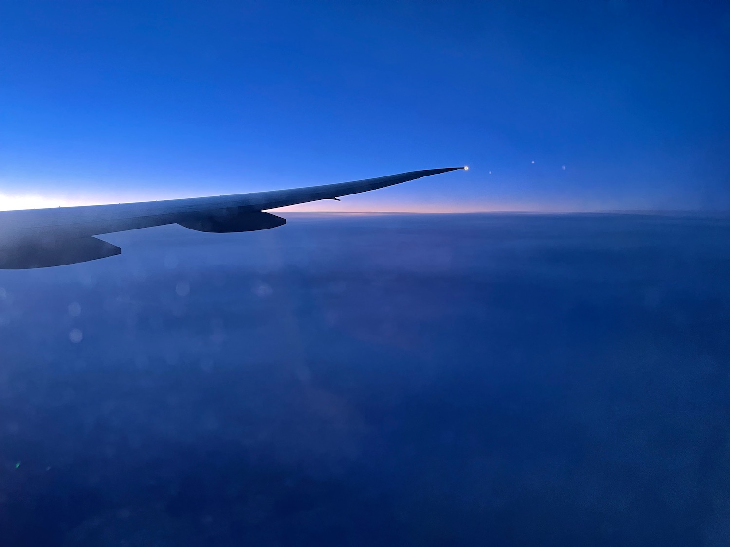 Air France 777-300ER wing in flight at sunset, showcasing the blue sky and clouds, highlighting the airline's economy class travel experience.