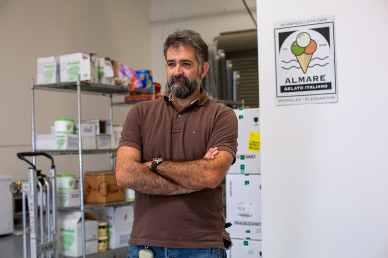 Man stands with crossed arms in front of open shelves