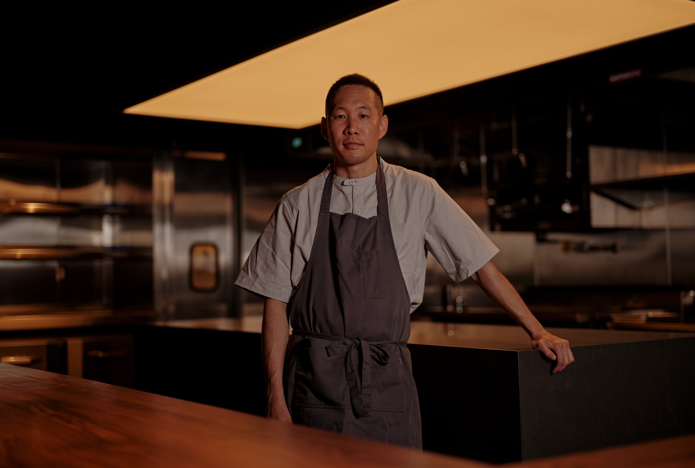 Brian Baik in a gray apron standing in the dining room at Corridor 109