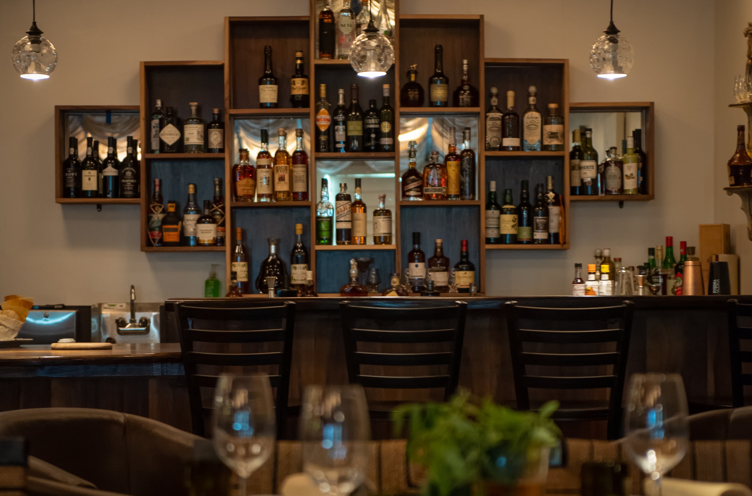 Shelves of wine on the wall behind a wood bar at Canto VI in Chatsworth, California.