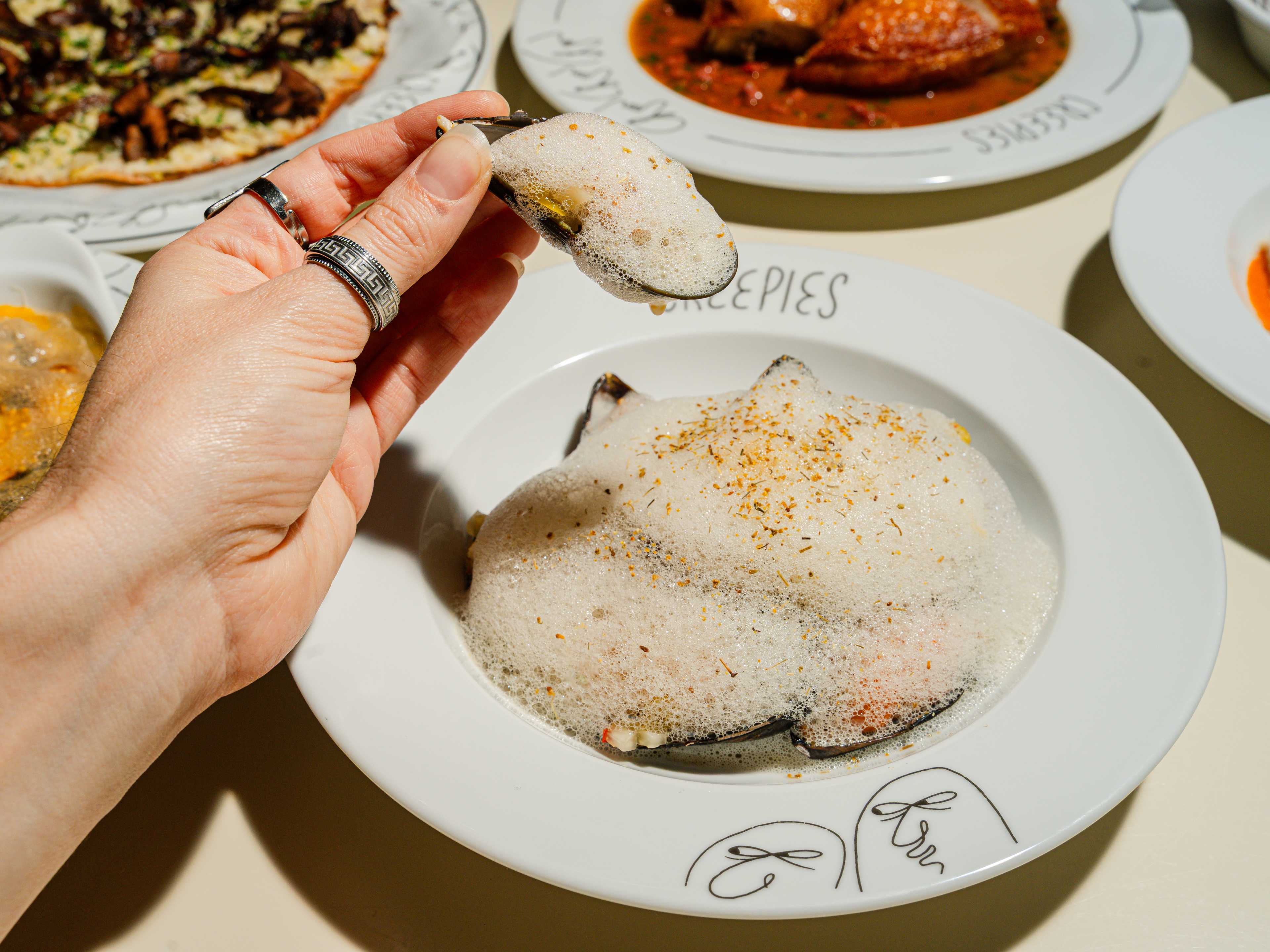 A hand picking up some mussels from Creepies.